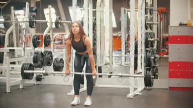 一位在健身房训练<strong>腿脚</strong>的运动员女子，手里拿着一个铁哑铃，身体向下倾
