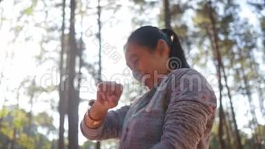 亚洲<strong>女人</strong>在花园里跑步前，在手腕上的智能<strong>手表</strong>屏幕上触摸设置健身应用程序。