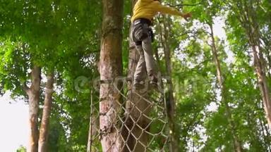 一个穿着安全装备的小男孩在森<strong>林探</strong>险公园的树梢上爬上了高空滑索。 室外