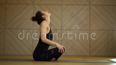 女孩在坐姿下做颈部<strong>热身运动</strong>。 年轻的美女在光极简工作室练习瑜伽