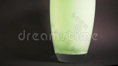 绿色浴盐缓慢地溶解在水的花瓶中，用粒子钻