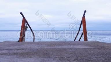 金属生锈的梯子进入旧码头的海景背景。