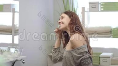 开朗的女人刷牙，用水冲洗浴室前镜