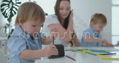 孩子削铅笔，妈妈和儿子坐在桌子旁一起画一幅画