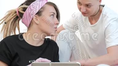 纹身大师女士与客户讨论素描，在工作室的平板电脑上<strong>展示图</strong>片。