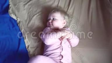 一个可爱的小醒了的幼儿在蓝色的毯子里旋转，然后在它的一侧转动，然后结冰。 小宝贝女儿