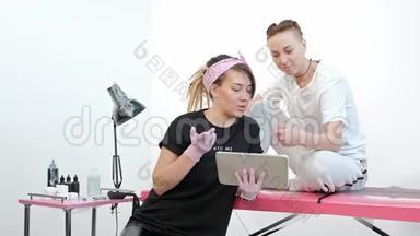 纹身大师女士与客户讨论素描，在工作室的平板电脑上<strong>展示图</strong>片。