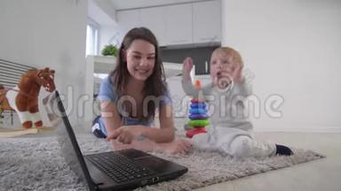 母子关系，快乐的妈妈和可爱的小男孩一起在笔记本电脑上看动画片，拍拍躺在上面的手