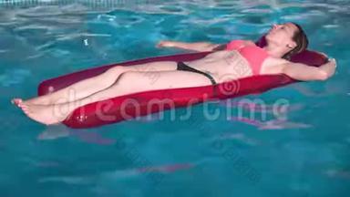 年轻快乐的女人在晴天在蓝色游泳池里放松充气游泳池玩具。