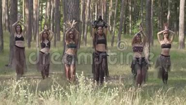 穿着森林居民或魔鬼的戏剧服装的年轻妇女在森林里跳阿拉伯舞蹈，表演香水或