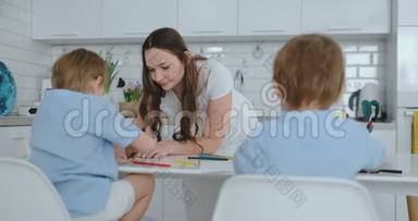 一个年轻的女人帮助孩子们在厨房里画画