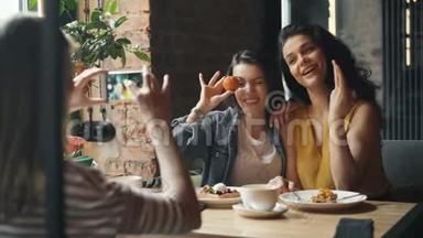 漂亮的年轻女士在咖啡馆里拍照，摆着智能手机摄像头
