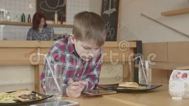 小男孩在咖啡馆吃饭时打电话
