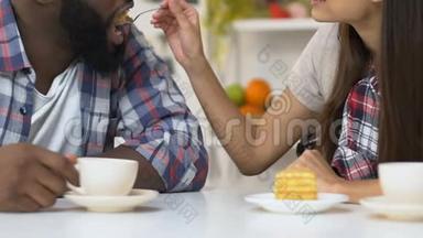 女孩用美味的蛋糕喂非洲裔美国男友，情侣喝咖啡