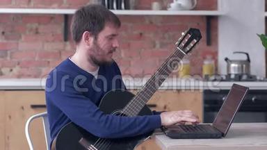 开朗的音乐家练习弹吉他，使用笔记本电脑和在线视频教程和<strong>快乐音乐</strong>