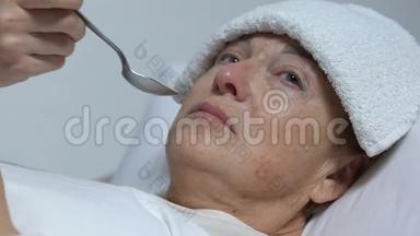 护士用毛巾喂哭泣的老妇人额头，病后残疾