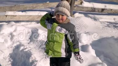 冬天，小可爱的男孩在外面的雪地里玩耍。 背景是一片雪林.. 那个男孩朝雪扔