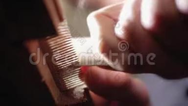 工匠用砂纸手工打磨一把木梳，靠近底部。 4千克
