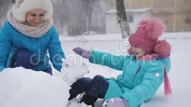 妈妈和她的小女儿在冬天玩得很开心，在街上<strong>堆雪人</strong>。