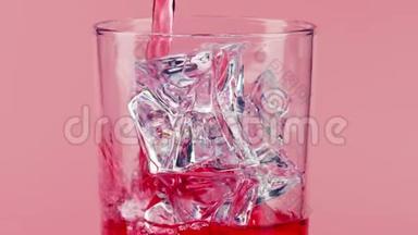 将红色软饮料<strong>倒入</strong>带有粉红色背景的冰块的玻璃<strong>杯中</strong>，慢镜头对准红色
