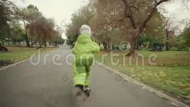 穿绿色连体衣的孩子在公园里骑摩托车。