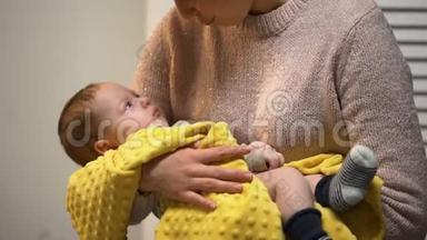 年轻的妈妈抱着可爱的新生婴儿，和他说话，爱