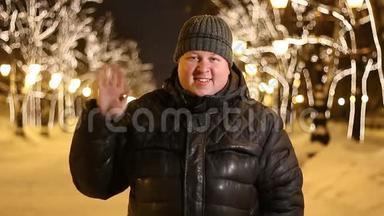 一位身穿黑衣的英俊胖子的画像在冬天的城市街道的夜晚挥舞着他的手