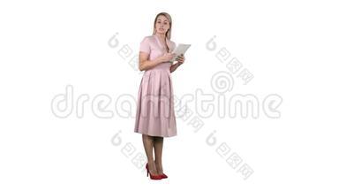 穿着粉红色衣服的女<strong>青年</strong>女士站着，拿着平板电脑，在白色背景上给相机<strong>演讲</strong>。