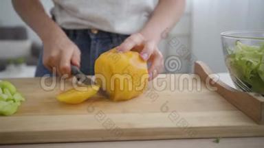 一位年轻女子用锋利的刀在厨房的桌子上切着大黄番茄。 健康观念