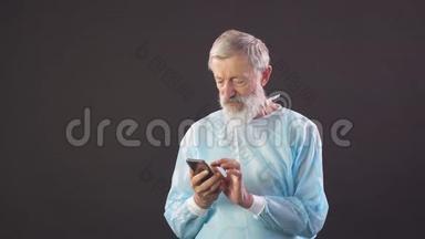 旧外科医生的画像。 <strong>老</strong>外科医生在黑暗的背景下使用智能手机。