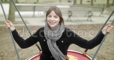 快乐<strong>活泼</strong>的女人在操场上坐在秋千上玩得很开心。