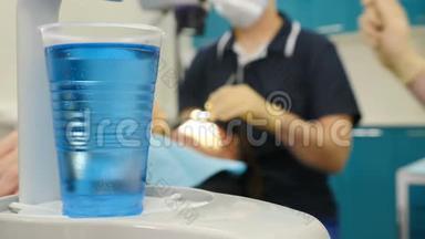 在第一个计划中用蓝色液体拍摄塑料<strong>玻璃片</strong>，并模糊牙医和助理制作牙科手术。