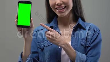 年轻的亚洲女士展示绿色屏幕智能手机，应用程序开发