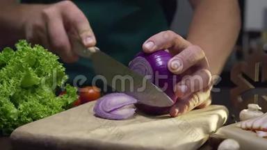 厨师在厨房的木板上用锋利的刀切下红色的洋葱，并关闭烹饪蔬菜的视频