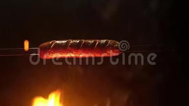 用扦子刺穿的全景浅汁香肠挂在炽热的火焰上。 大量的火，火苗上的香肠。