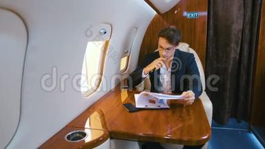 忙碌的商人在私人飞机上飞行时处理文件。 商务舱。
