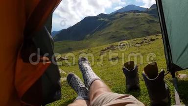 穿袜子的男腿在夏天的绿色山谷里的帐篷里欢快地移动