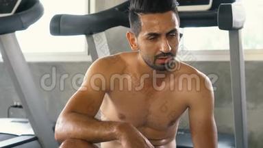 在健身房锻炼后，疲惫的男人一边擦汗一边放松