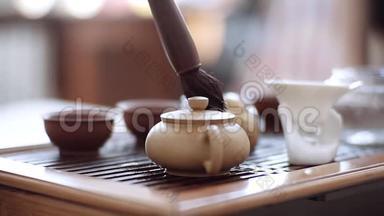 在茶刷的帮助下，手从一滴沸水中擦拭一个<strong>小水壶</strong>