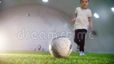 室内足球场 一个小男孩跑到球前，拿着球跑开