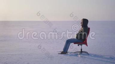 围着一个穿着温<strong>暖</strong>外套和引擎盖的商人围着雪<strong>场</strong>背景上的红色椅子走来走去。