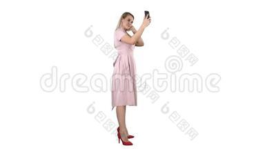 美丽的女人打扮成白色背景看着她的手机。