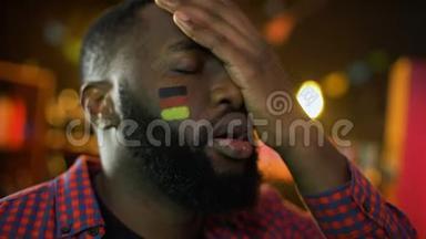 失望的德国足球迷，脸上挂着旗子，球队输了