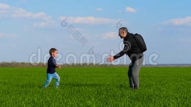 一个快乐的孩子穿过绿草，跑到父亲的怀里，父亲把孩子抱在怀里，拥抱他