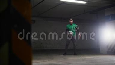 地下停车场。足球运动员训练他的足球技术。把球踢向空中然后
