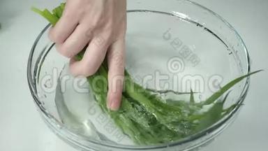 女人手`葱，慢动作。 女人的手在一杯水中洗了一串洋葱