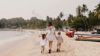镜头跟随快乐的年轻母亲和两个小孩子在热带度假慢动作的异国海滩散步。