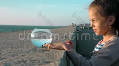 欢快可爱的小女孩在水族馆里玩小鱼温暖的夏天日落海边