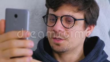 快乐的年轻人戴眼镜在智能手机上说视频聊天，在线约会。