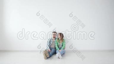 年轻的幸福夫妇正坐在空荡荡的房间里，打算在新房子里布<strong>置家</strong>具
